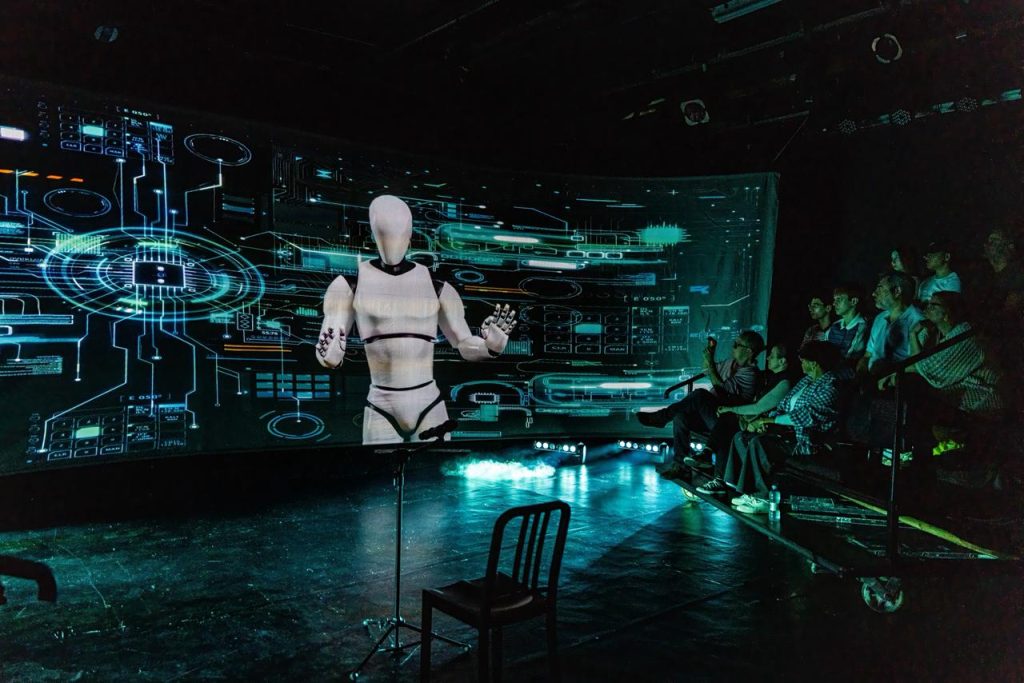 Espetáculo com avatares digitais em palco durante apresentação teatral