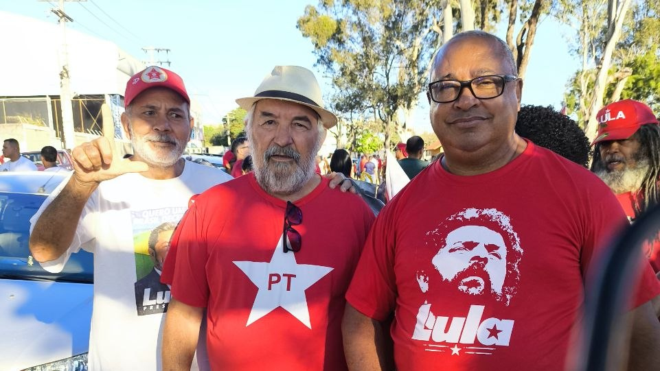 Participantes posam ao ar livre com camisetas e bonés de apoio a Lula e ao PT