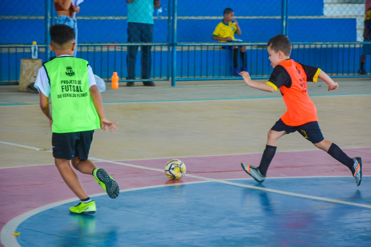 Crianças jogam futsal em uma quadra esportiva