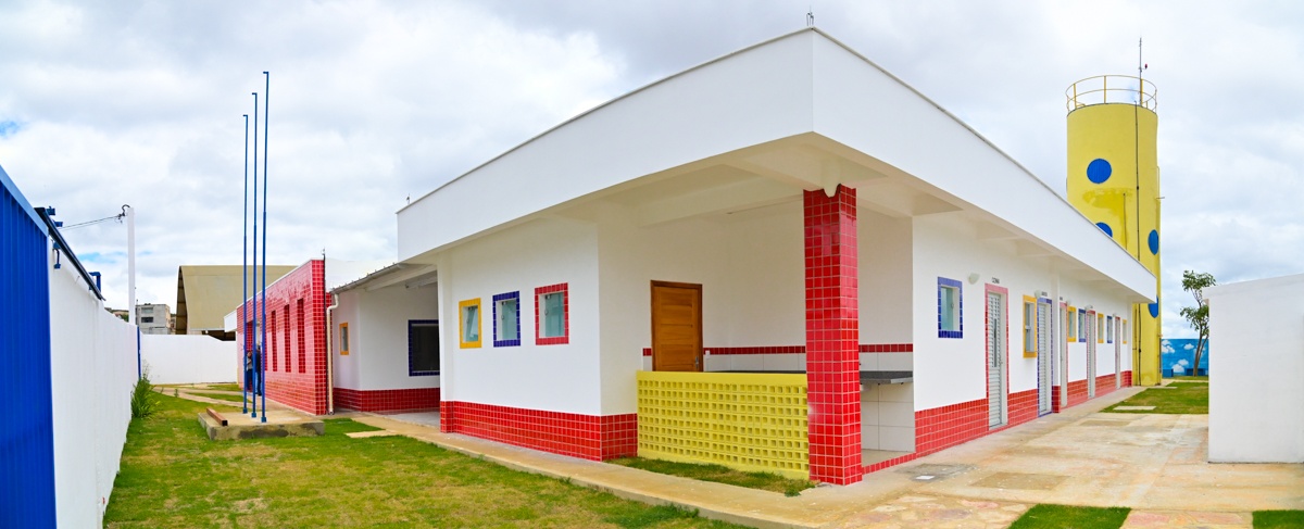 Prédio escolar com paredes brancas, revestimentos vermelhos e janelas coloridas em Vitória da Conquista
