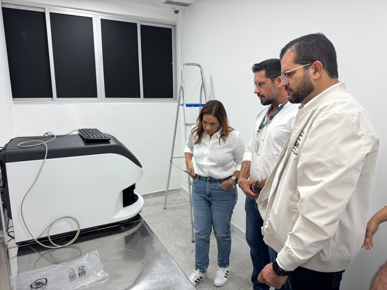 Grupo acompanha equipamento em sala de laboratório durante visita às instalações de saúde.