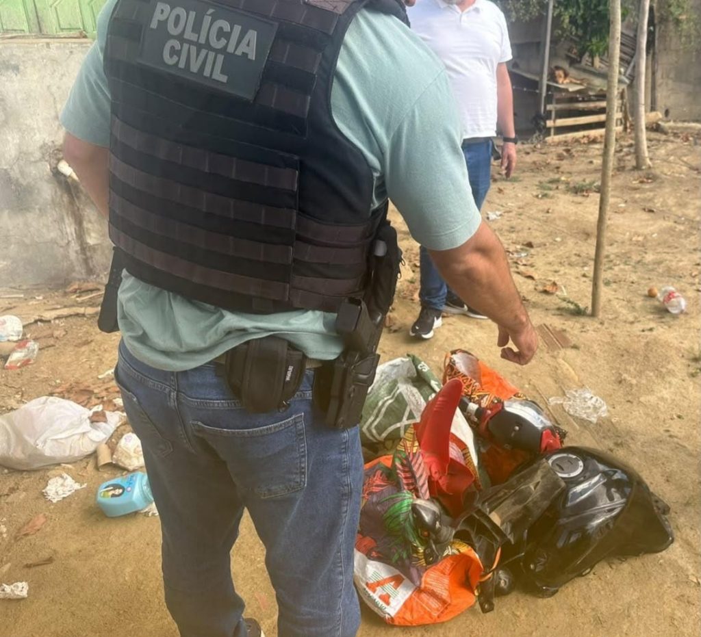 Agente com colete da Polícia Civil ao lado de tanque e carenagens de motocicleta encontrados no chão