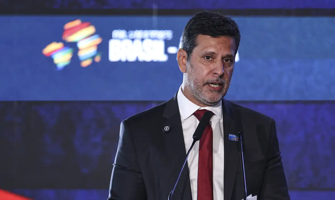Ministro Leonardo Barchini de terno e gravata vermelha, falando ao microfone em evento