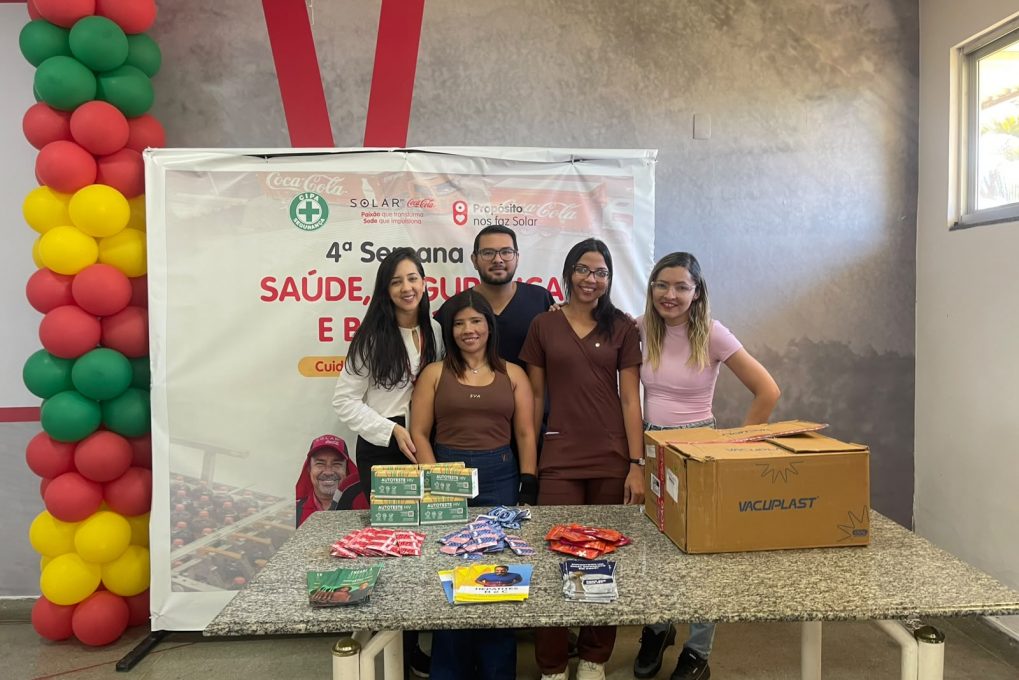 Equipe reunida atrás de mesa com materiais informativos em ação de saúde