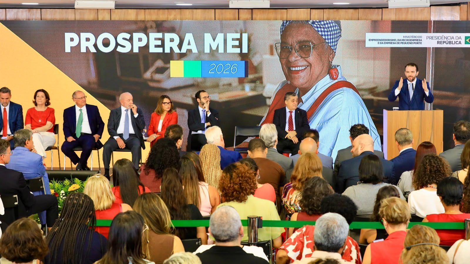 Autoridades e participantes durante cerimônia de anúncio do Prospera MEI, com painel do programa ao fundo